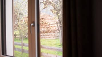 Une fenêtre donnant sur une pile de bûches et une clôture en bois.