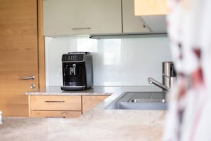 Eine Küche mit Kaffeemaschine auf der Arbeitsfläche, einem Spülbecken und Holzausbau.