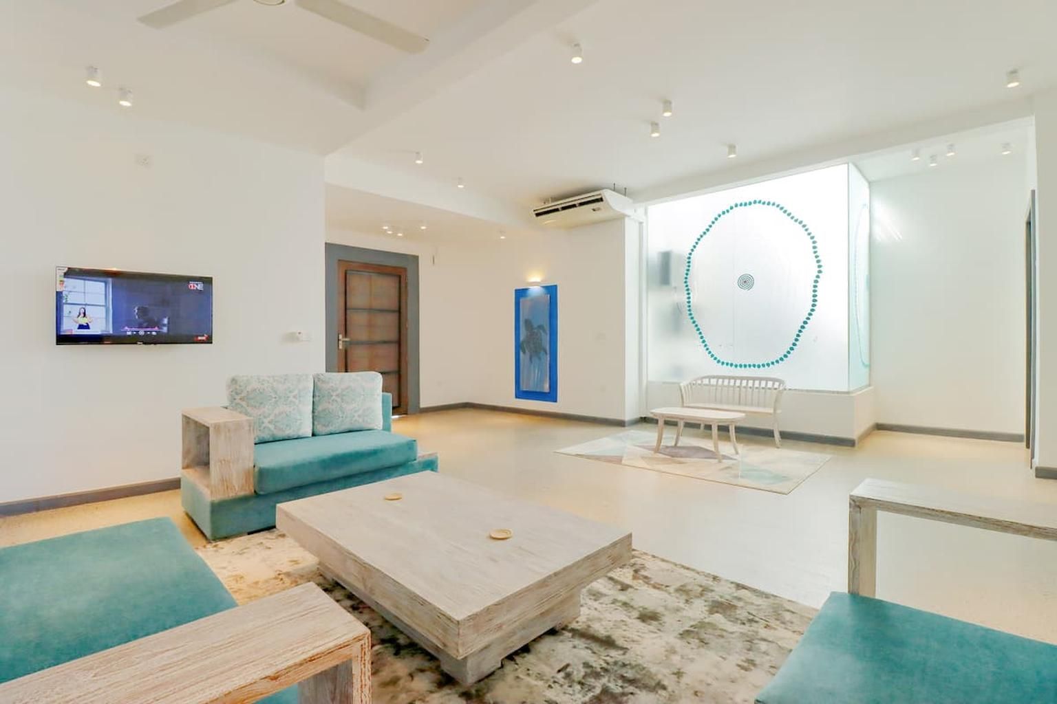 A modern living room with a sofa, a coffee table, and a TV mounted on the wall.