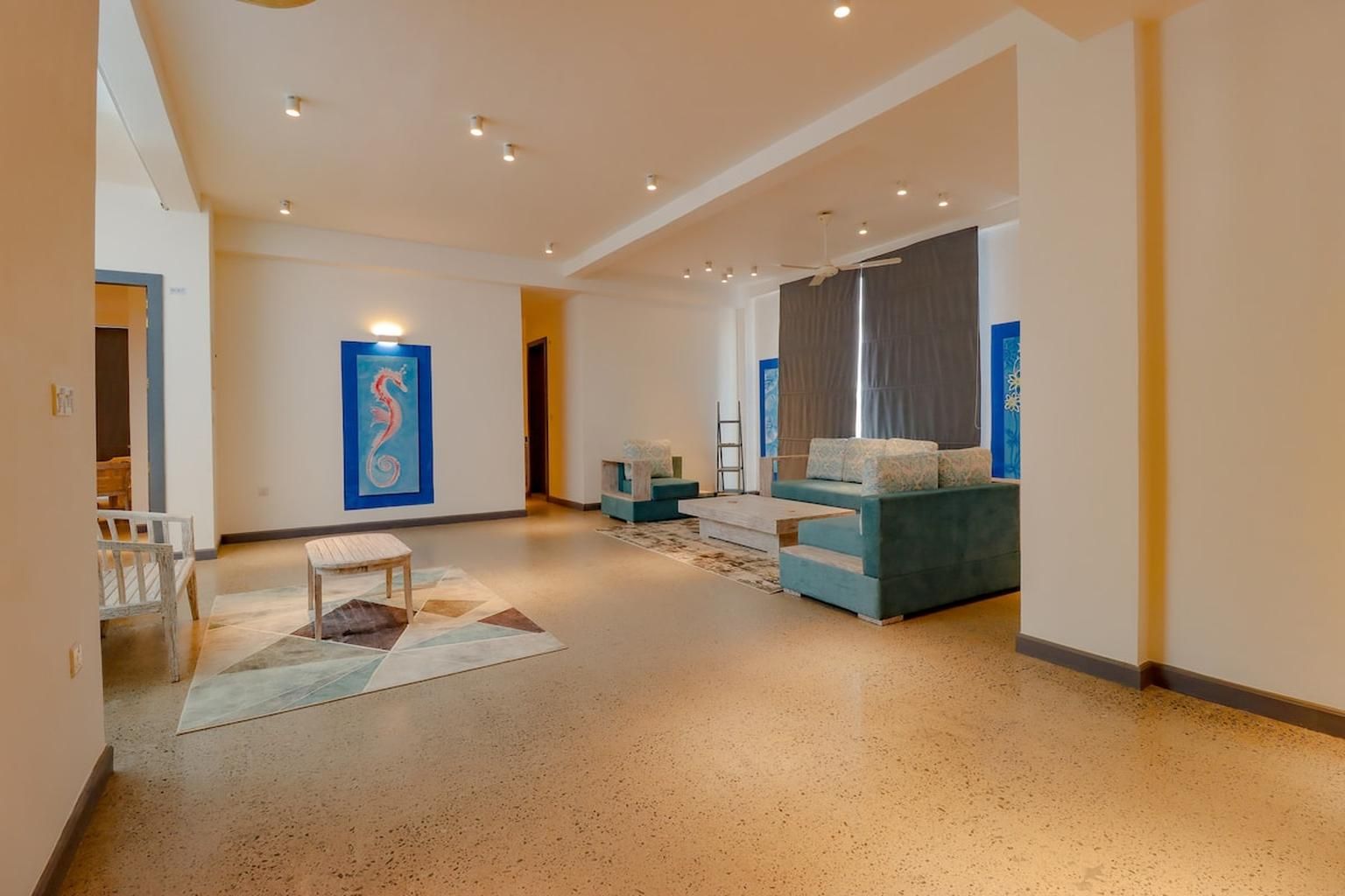 A spacious living area with a sofa, a coffee table, and a painting on the wall.