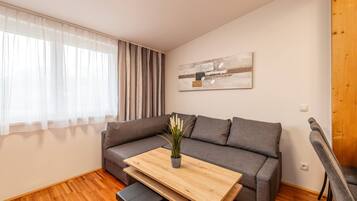 Ein modernes Wohnzimmer mit einem grauen Sofa, einem Holztisch und einer Topfpflanze.
