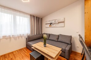 Ein modernes Wohnzimmer mit einem grauen Sofa, einem Holztisch und einer Topfpflanze.