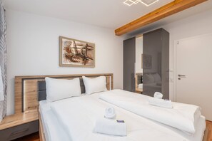 Ein Hotelzimmer mit einem großen Bett, einem Holzkopfstück, einem Gemälde an der Wand und einer Tür mit einem Spiegel.