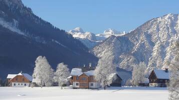 Schneebedeckte Landschaft mit Holzhäusern und Bergen im Hintergrund.