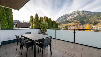 Une terrasse avec une table et des chaises, donnant sur un paysage montagneux.