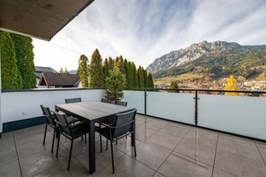 A terrace with a table and chairs, overlooking a mountainous landscape. - Drei Berge Blick Apartment 3 (Gröbming)