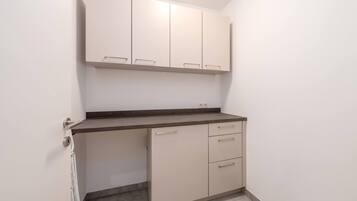 Een compacte kitchenette met een aanrecht, kastjes en een deur.