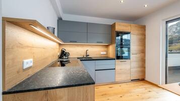 Una cocina moderna con muebles de madera, horno empotrado y un amplio ventanal con vistas al exterior.