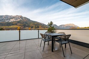 Eine Terrasse mit Tisch und Stühlen mit Blick auf einen See und Berge.