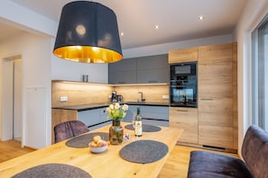 Eine moderne Küche mit einem Holztisch, grauen Tischsets und einer Vase mit Blumen.