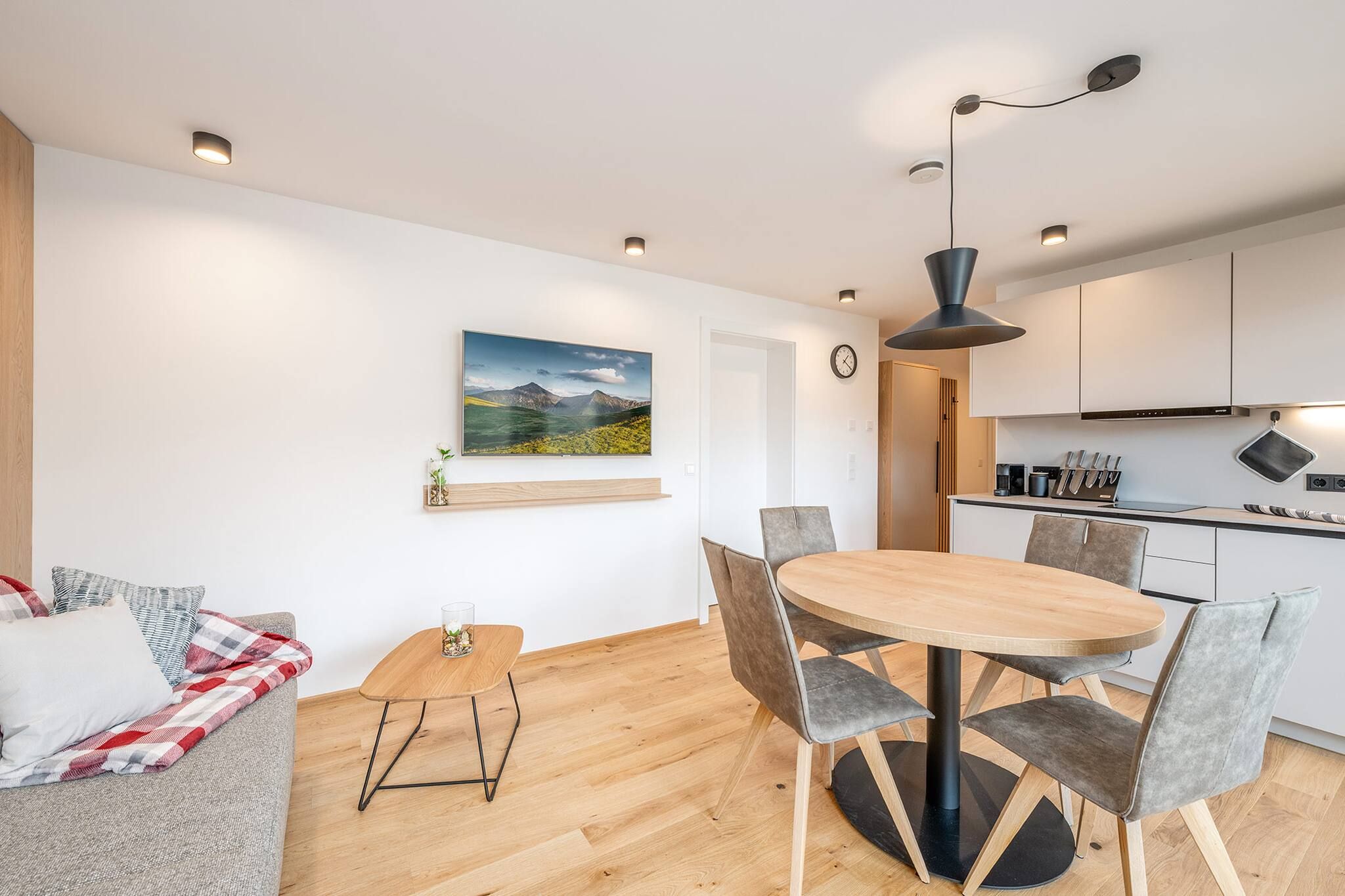 A modern living space with a dining area, kitchen, and a sofa.