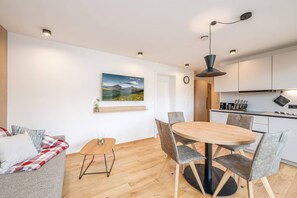 A modern living space with a dining area, kitchen, and a sofa.