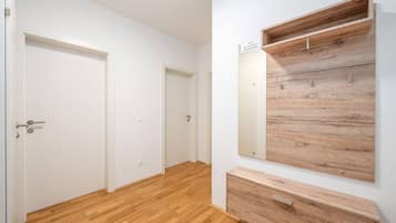 A hallway with wooden flooring, white walls, and a built-in wooden shelf unit with a nameplate.