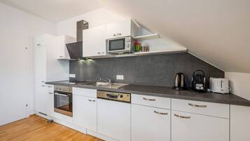 Eine moderne Küche mit weißen Schränken, Backofen, Mikrowelle, Kaffeemaschine und Toaster.