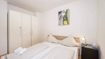 Ein Hotelzimmer mit einem Bett, zwei Nachttischen, einem Kleiderschrank und einem Bild an der Wand.