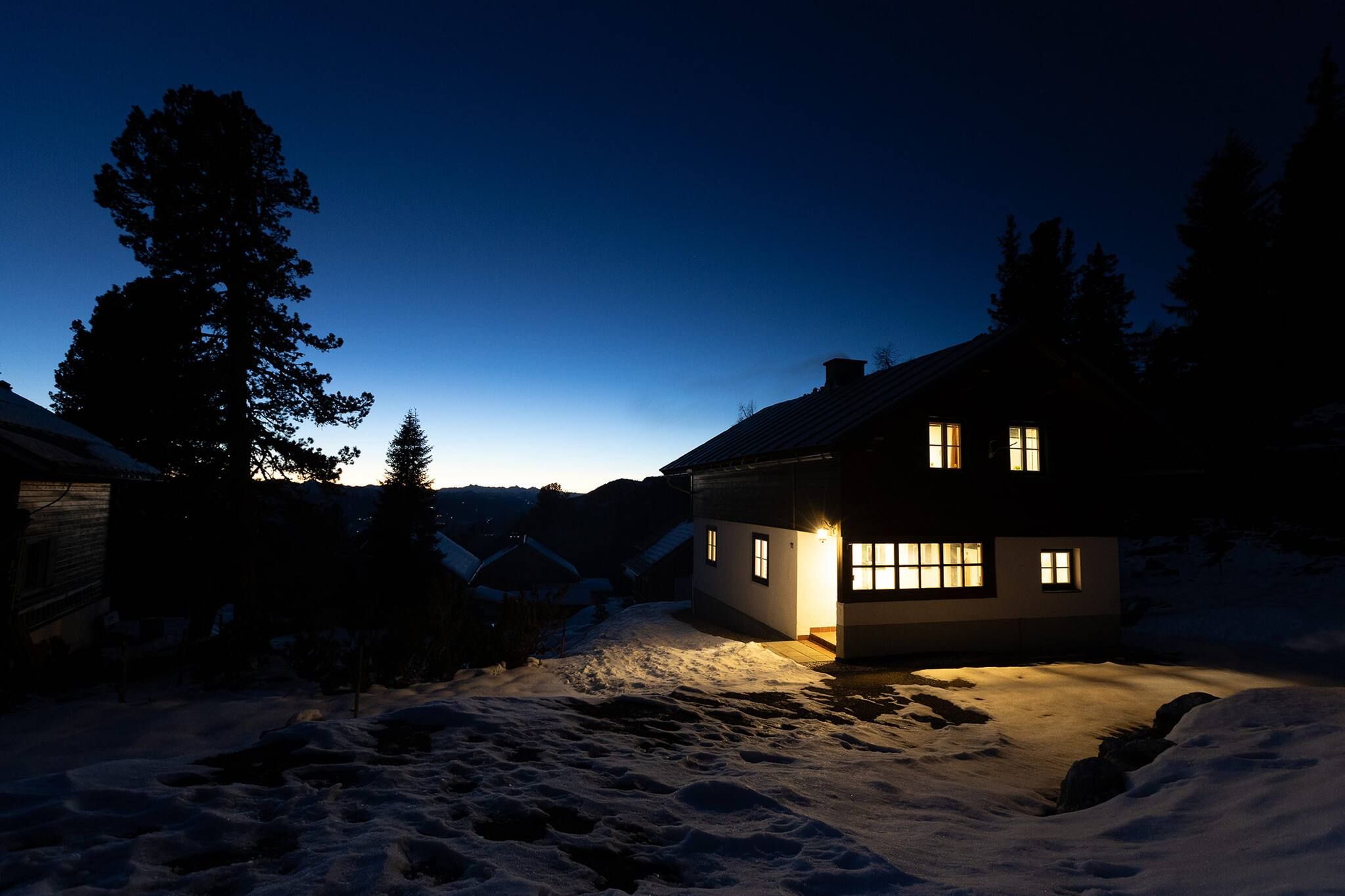 Ein Haus mit verschneitem Hof im Abenddämmerung.
