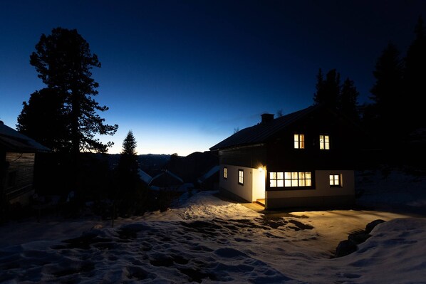 Ein Haus mit verschneitem Hof im Abenddämmerung.