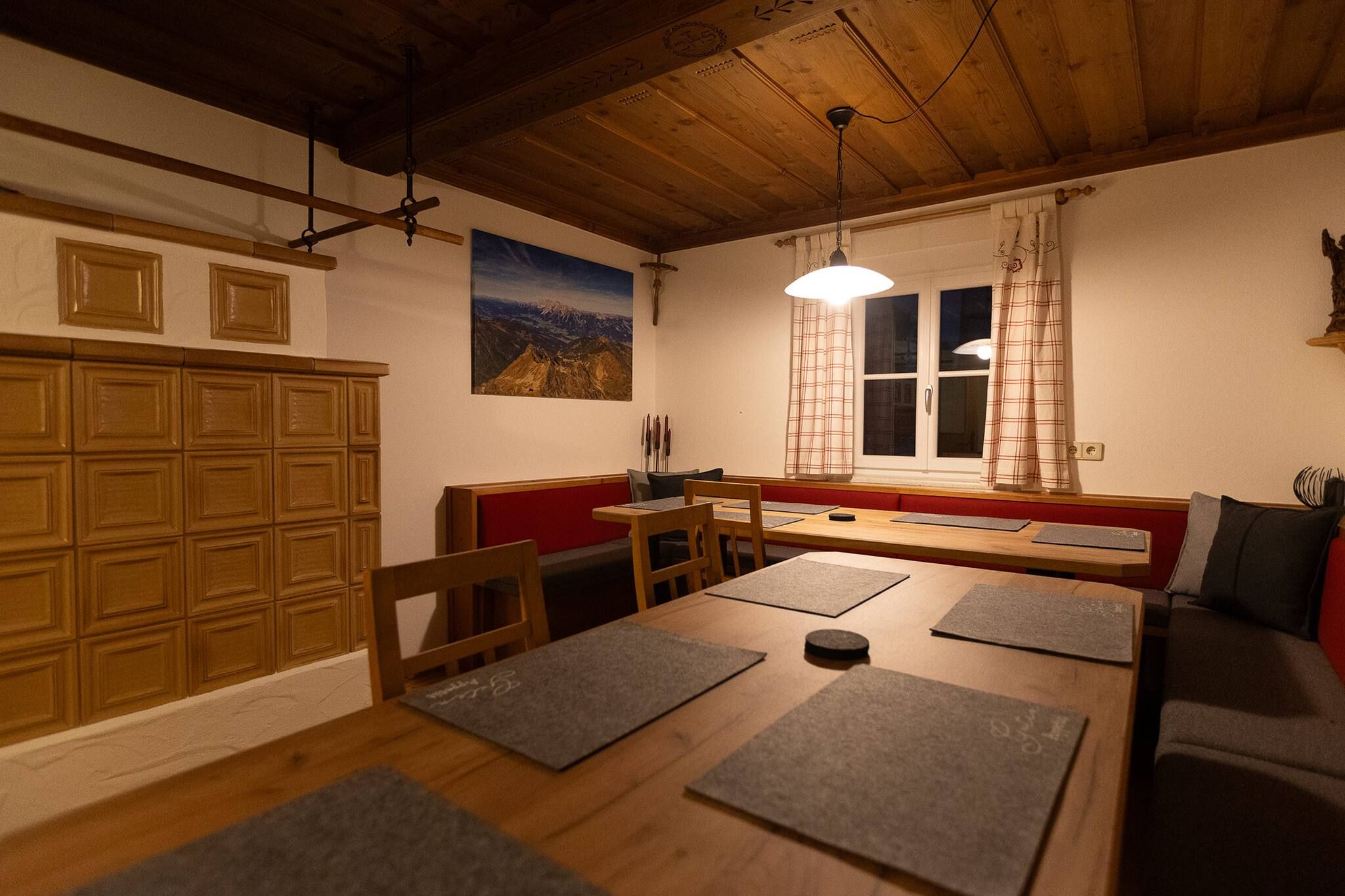 A cozy dining area with a wooden table, benches, and a view of the mountains through a window.