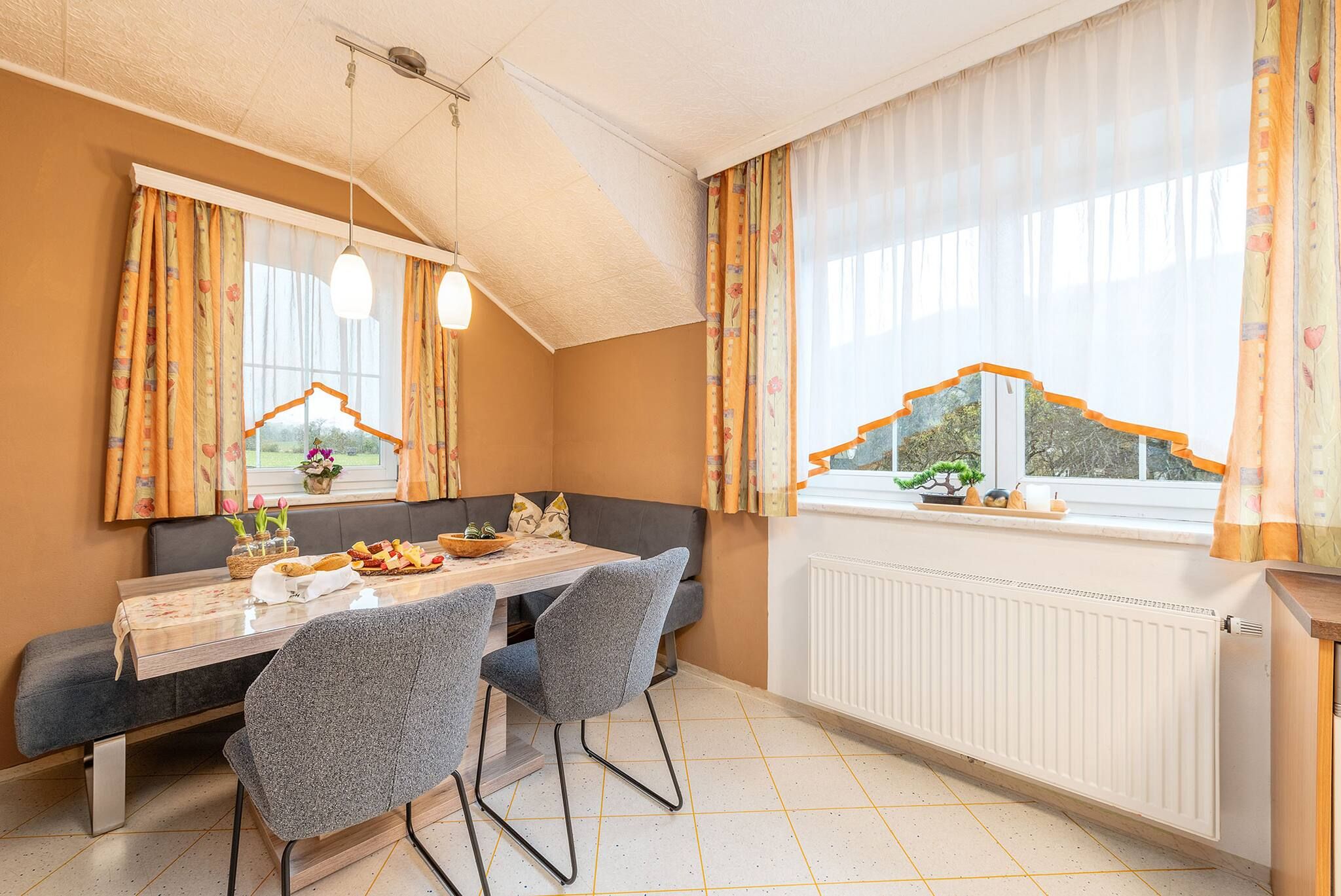 A dining area with a table, chairs, and a view of the outdoors through large windows.