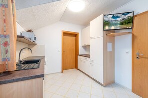 Eine kleine Küche mit Spüle, Schränken und einem Fernseher, der über der Arbeitsfläche angebracht ist.