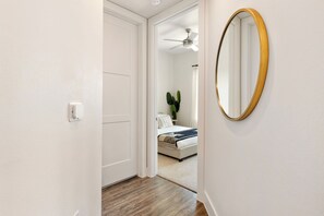 A hallway leading to a bedroom with a bed, a ceiling fan, a potted plant, and a mirror. - Luxury Apartment w/ 1B1B For Your Retreat SHI 2301 (Austin)