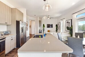 A modern kitchen with a central island, stainless steel appliances, and pendant lighting. - Luxury Apartment w/ 1B1B For Your Retreat SHI 2301 (Austin)