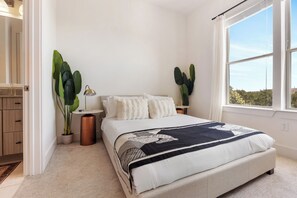 A bedroom with a bed, two nightstands, a lamp, and two large potted plants. - Luxury Apartment w/ 1B1B For Your Retreat SHI 2301 (Austin)