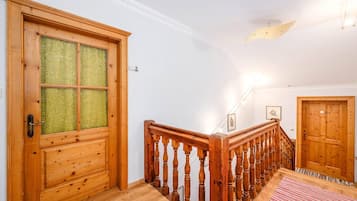 Eine Holztreppe mit Geländer, eine Glastür mit Holzrahmen und ein rot-weiß gestreifter Teppich auf dem Boden.