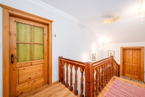 Eine Holztreppe mit Geländer, eine Glastür mit Holzrahmen und ein rot-weiß gestreifter Teppich auf dem Boden.