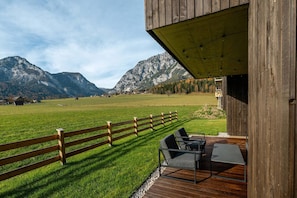 Eine Holzterrasse mit Gartenmöbeln, ein Holzzaun und Blick auf die Berge.