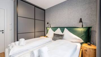 Ein modernes Hotelzimmer mit einer großen Schiebetür, einem Bett mit weißen Laken, zwei Nachttischlampen und einem grünen Kopfteil.
