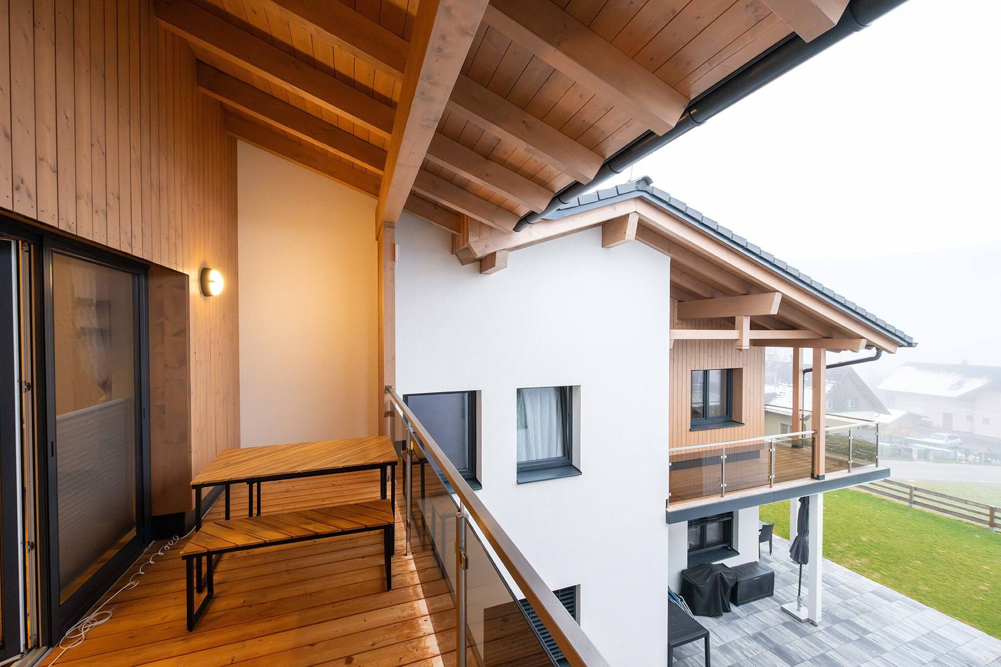 A modern building with a wooden deck, a staircase, and a balcony with outdoor furniture.
