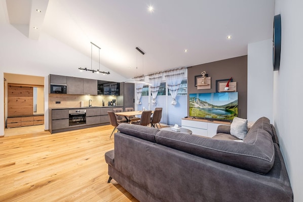 A modern living space with a kitchen, dining area, and a large sofa. - PanoramaAlpin Apartment (Aich-Assach)