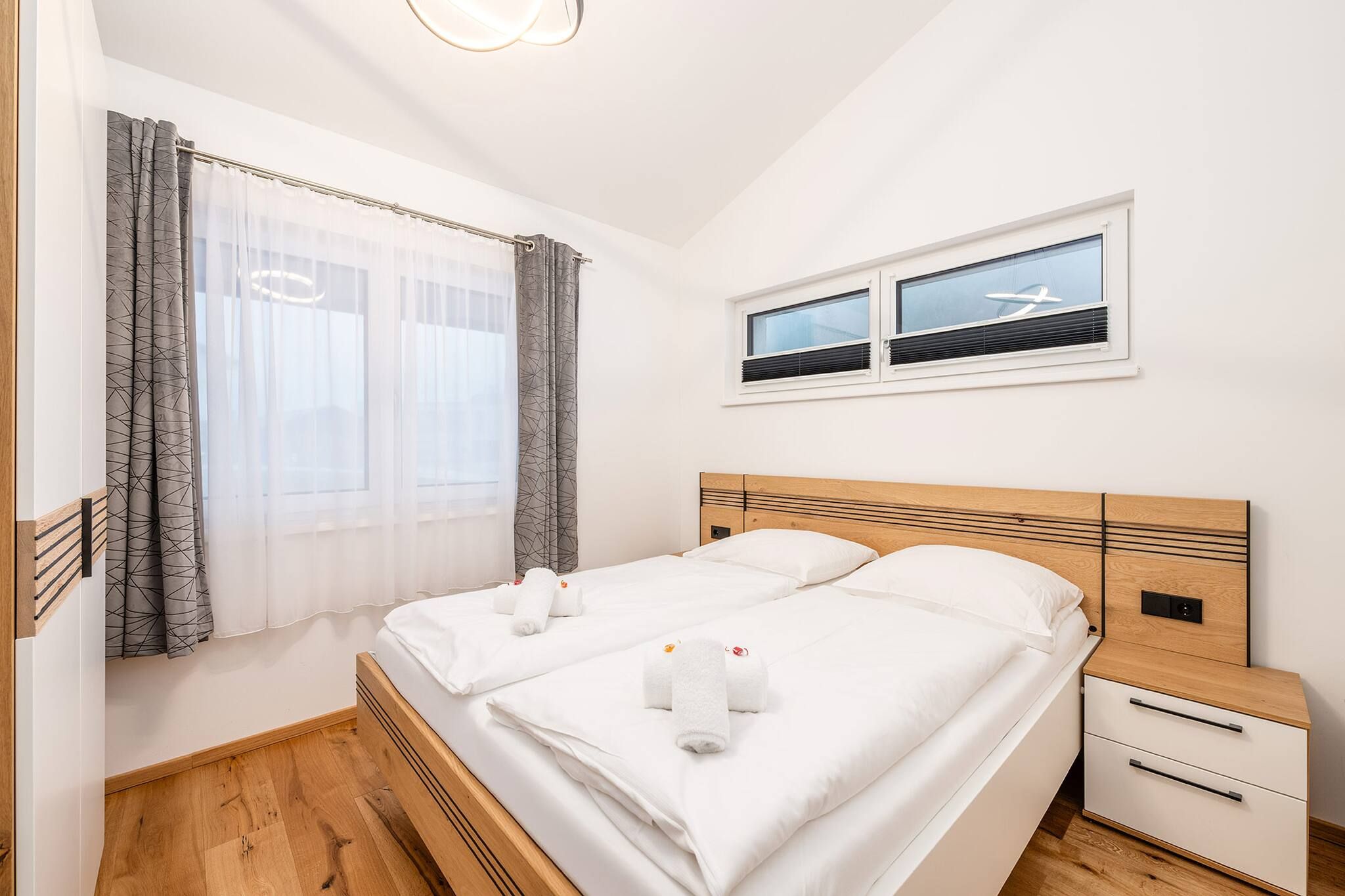 Una camera da letto con un letto, due comodini, una finestra con tende e un condizionatore d'aria a parete.
