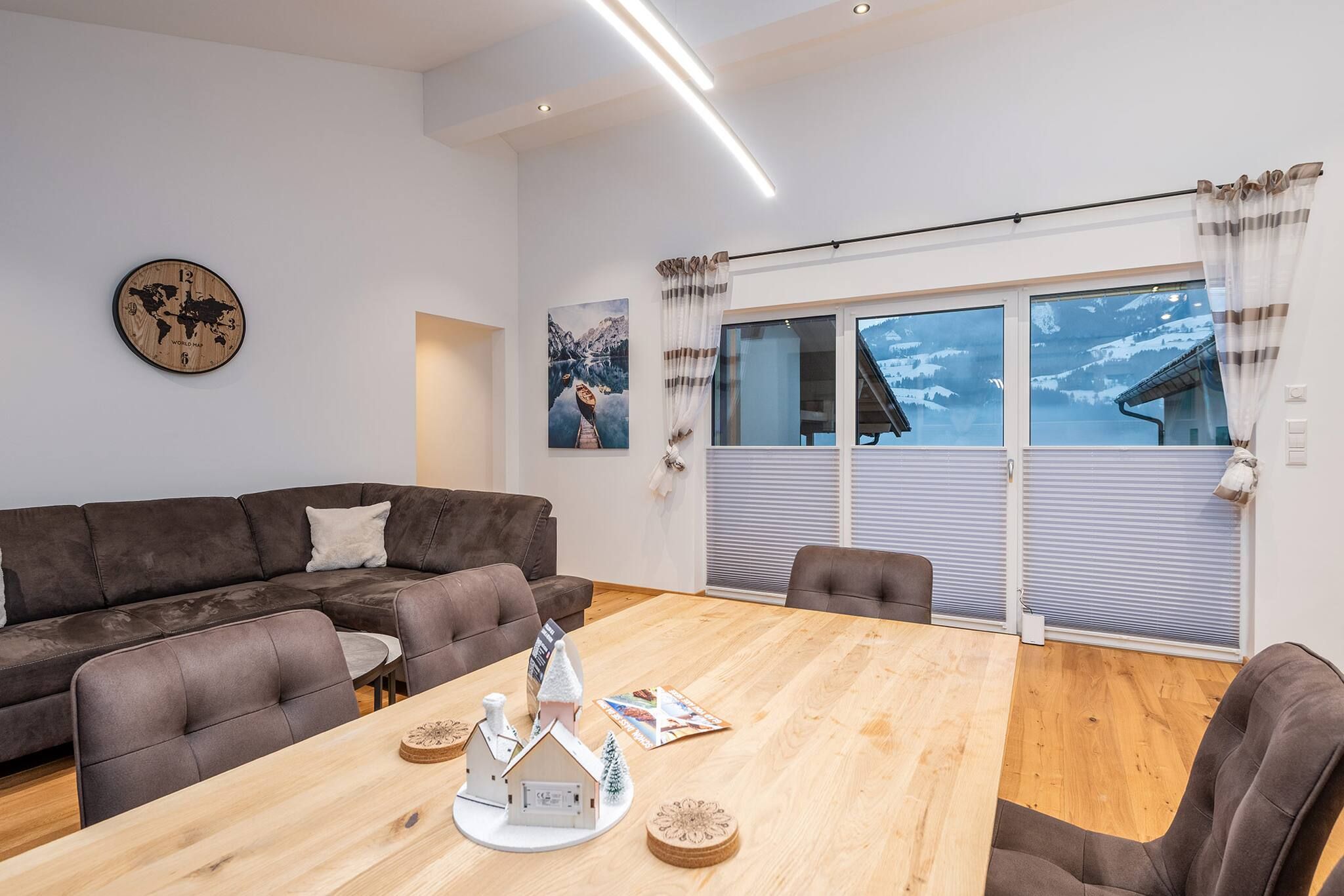 Un salon moderne avec un canapé en cuir marron, une table basse en bois et une horloge représentant une carte du monde accrochée au mur.