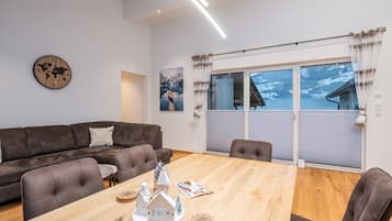 Un salon moderne avec un canapé en cuir marron, une table basse en bois et une horloge représentant une carte du monde accrochée au mur.