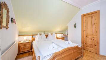 Ein Schlafzimmer mit einem hölzernen Bett, zwei Nachttischen, einem Heizkörper, einer Holztür und einem Spiegel an der Wand.