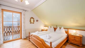 A bedroom with a wooden bed, a nightstand, a window with curtains, and a view of a balcony.
