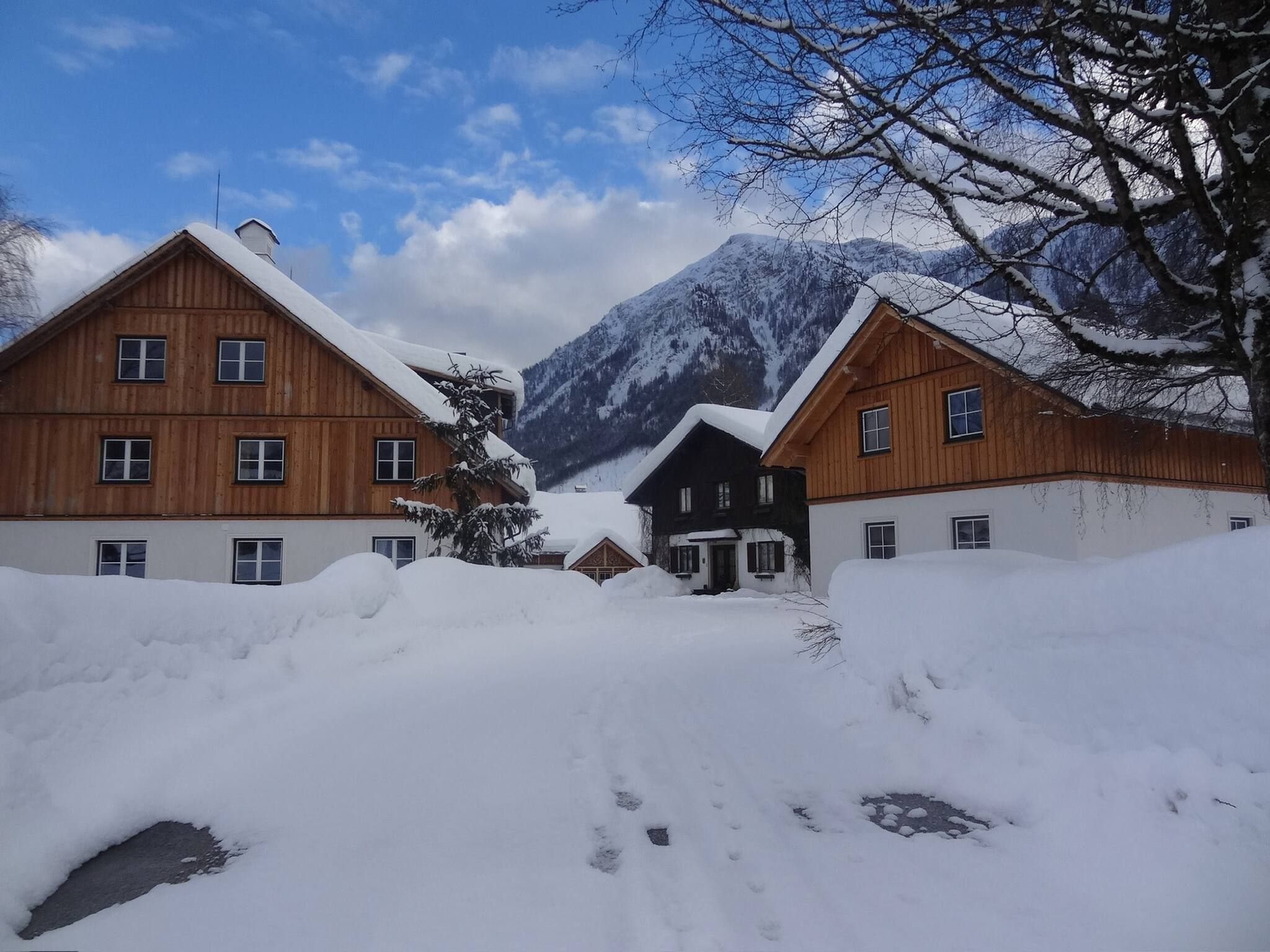 Ein verschneites Dorf mit Holzhäusern, ein Berg im Hintergrund und ein klarer Himmel.