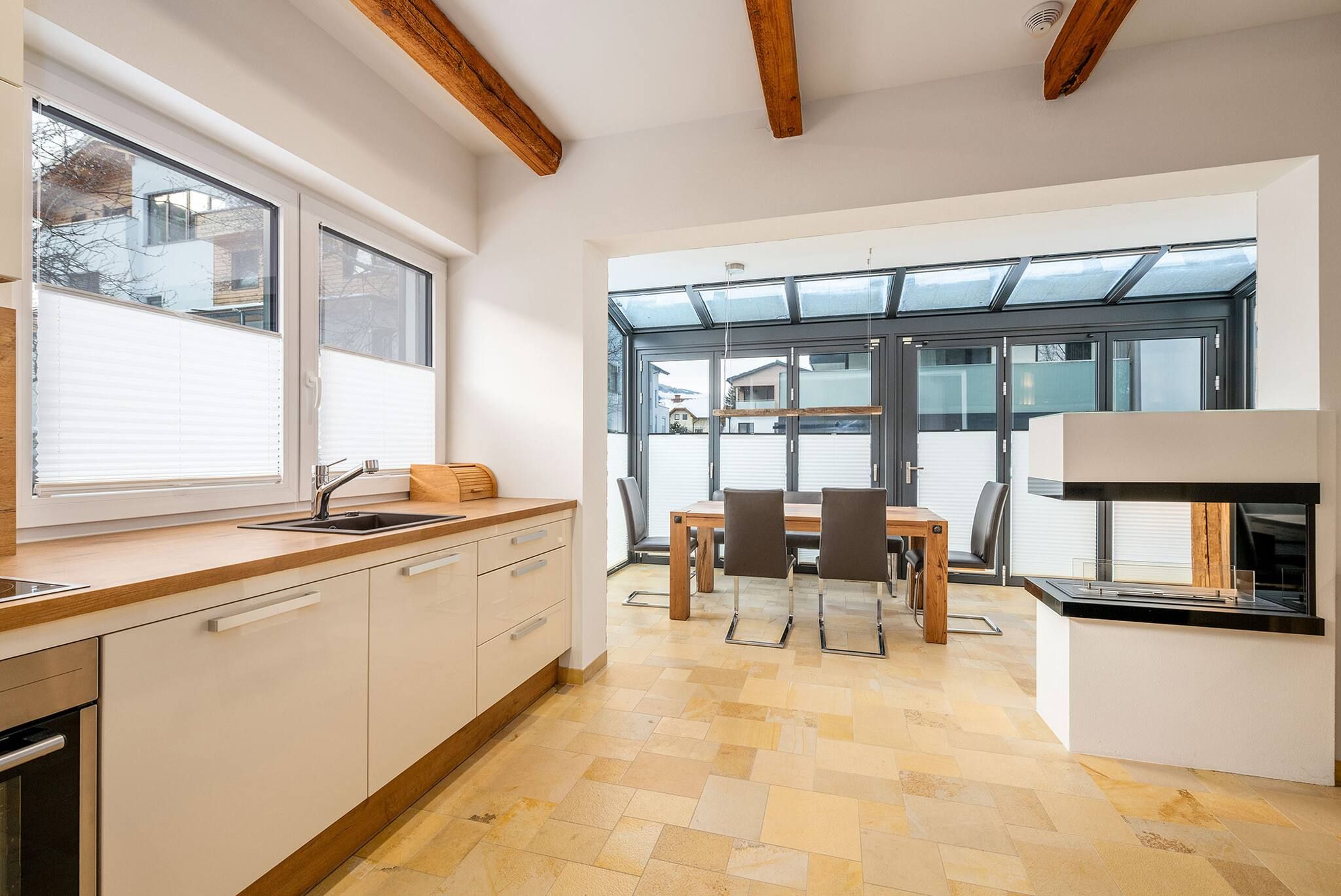Una cocina moderna con comedor, ventanas amplias y vigas de madera.