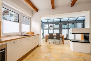 Una cocina moderna con comedor, ventanas amplias y vigas de madera.