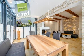 Ein modernes Interieur mit einem Holztisch, grauen Sofas und einer Wand mit Steinverkleidung.
