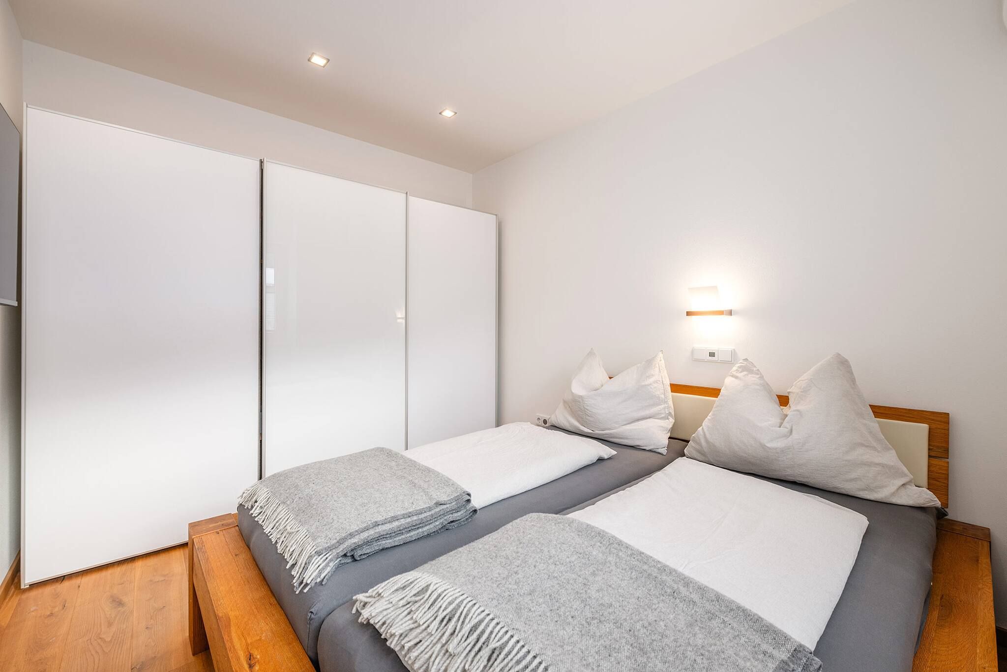 Un dormitorio con dos camas, un armario, una mesita de noche y una lámpara de pared.