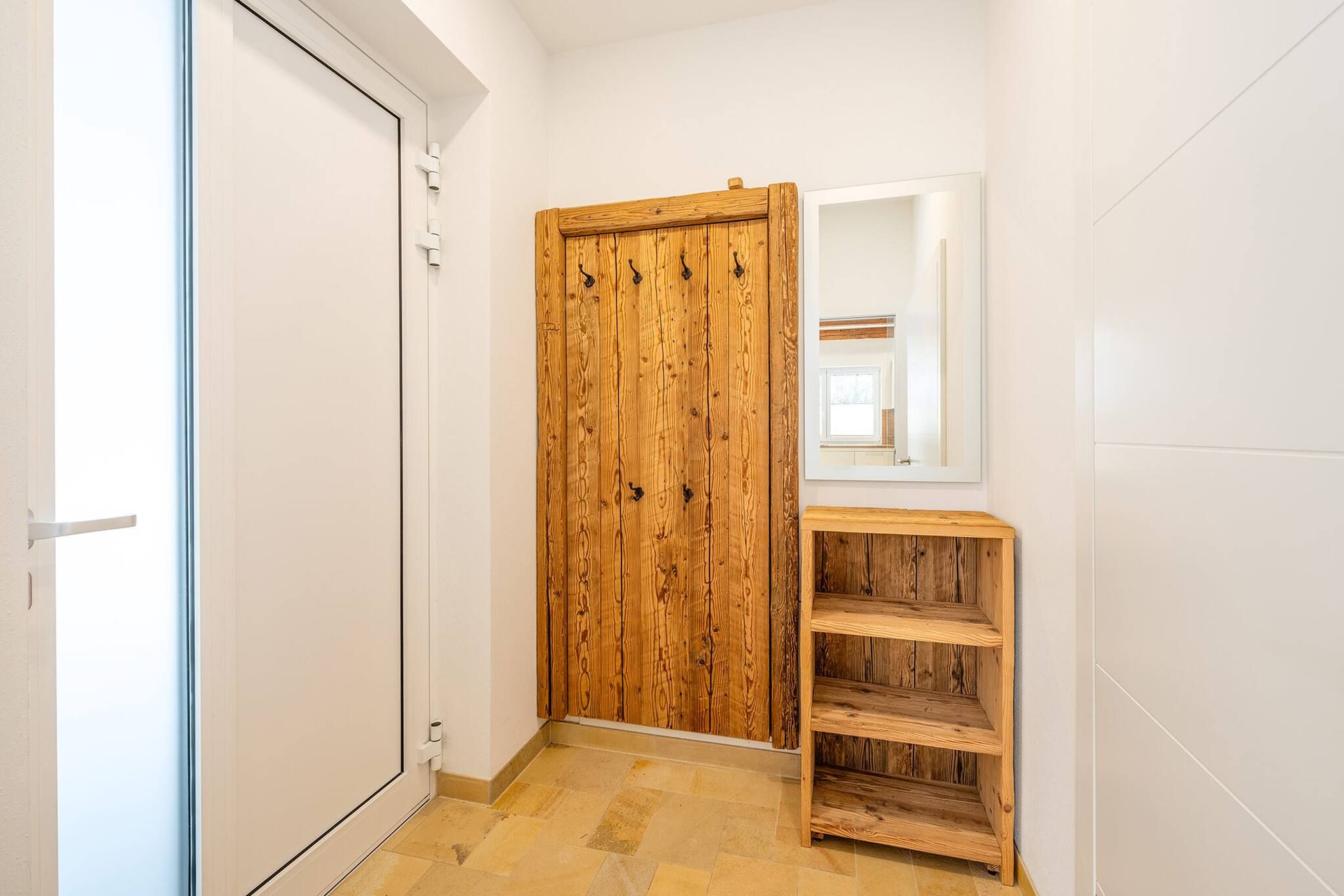 Un pasillo con un armario de madera, un espejo y una estantería de madera.