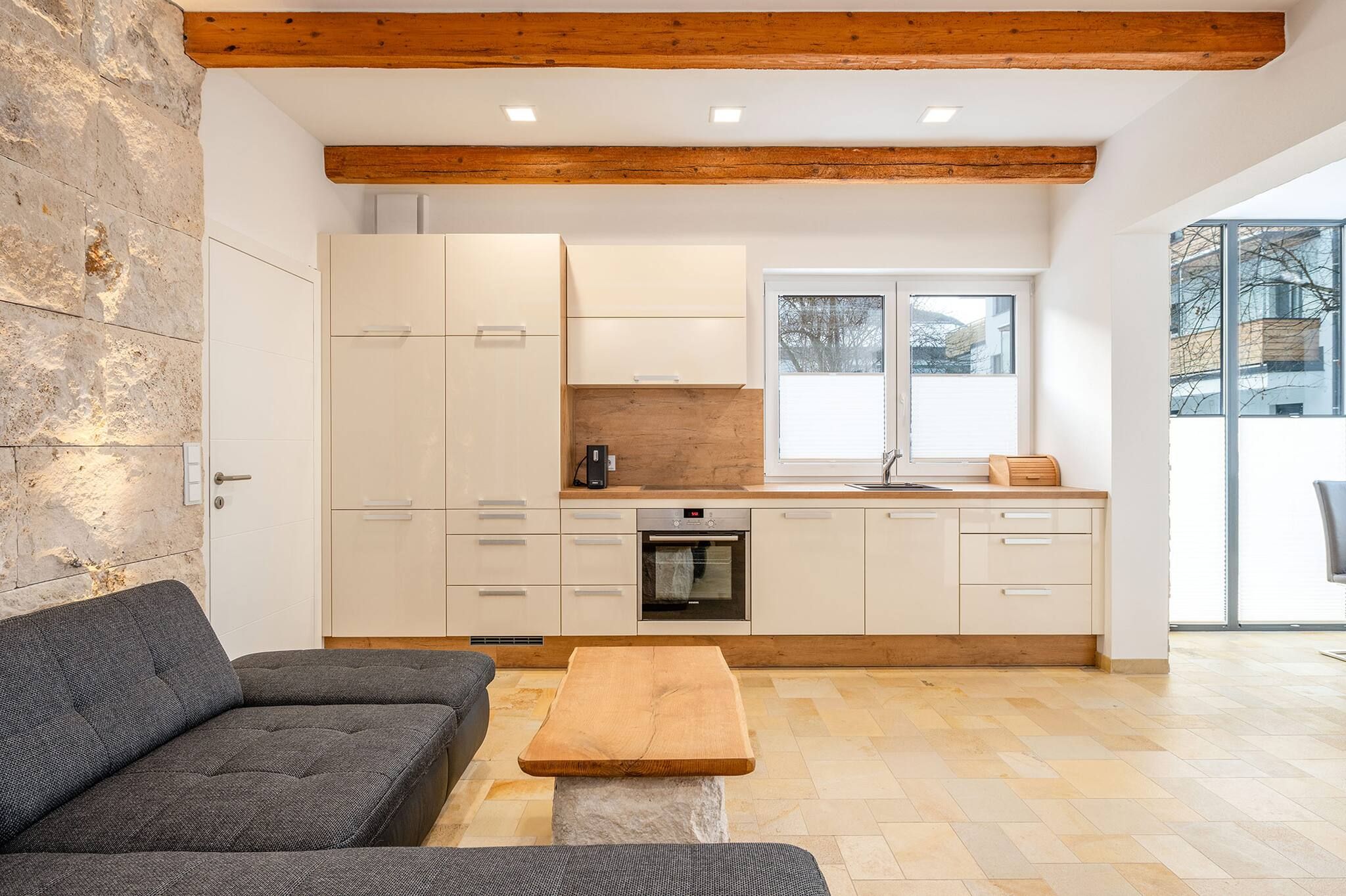 Una cocina moderna con armarios blancos, horno empotrado y ventana.