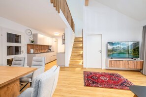 Ein stilvoller Wohnraum mit Küche, Essbereich und einer Treppe zu einer oberen Ebene.