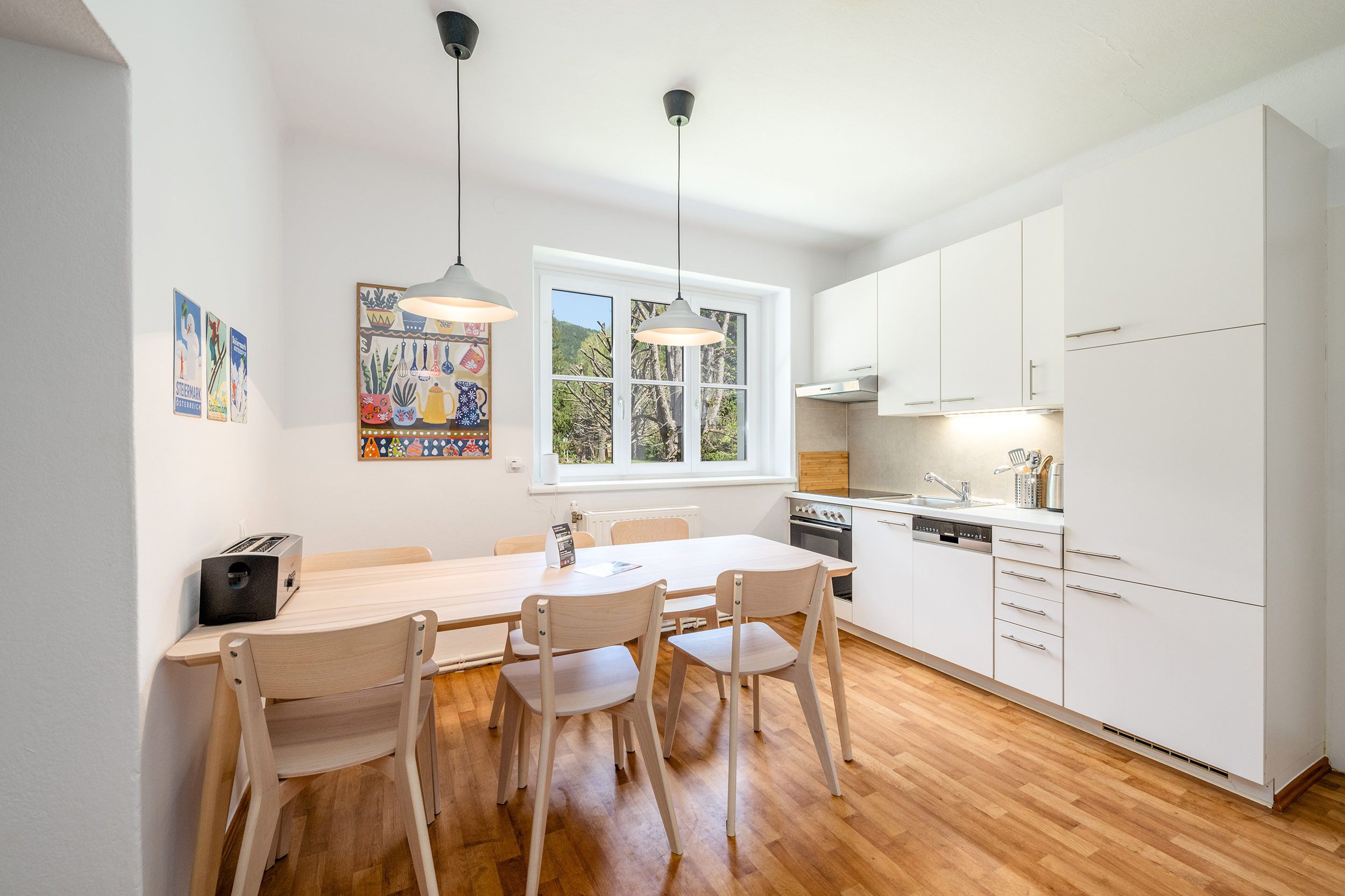 Una cucina moderna con mobili bianchi, un tavolo da pranzo in legno e sedie.