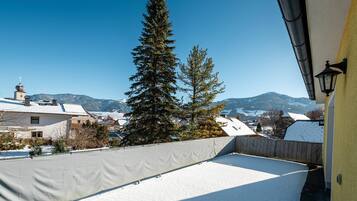 Ein mit Schnee bedecktes Dach mit Blick auf eine Stadt und Berge im Hintergrund.