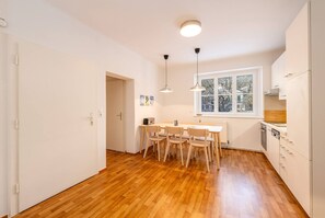 Una cucina con zona pranzo, pavimento in legno, pareti bianche e una finestra con vista.