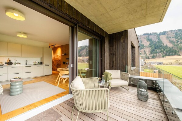 A modern kitchen with white cabinets and a dining area with a table and chairs. - Mountain Paradise - Grimming 4 (Gröbming)